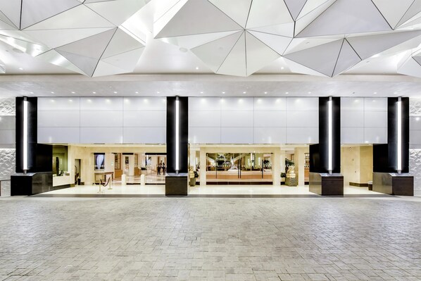 A spacious lobby with a geometric ceiling design, large pillars, and a tiled floor. - Hilton Los Angeles Airport (Los Angeles)
