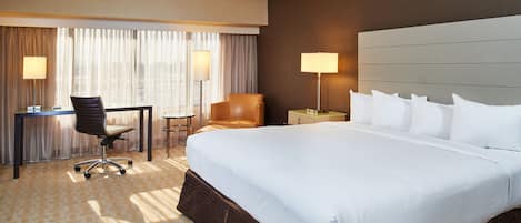 Habitación de hotel con una cama grande, un escritorio, una silla y dos lámparas.