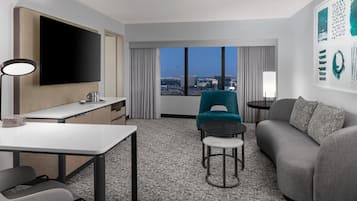 Una habitación de hotel moderna con televisión de pantalla plana, una mesa de comedor, un sofá y una silla.