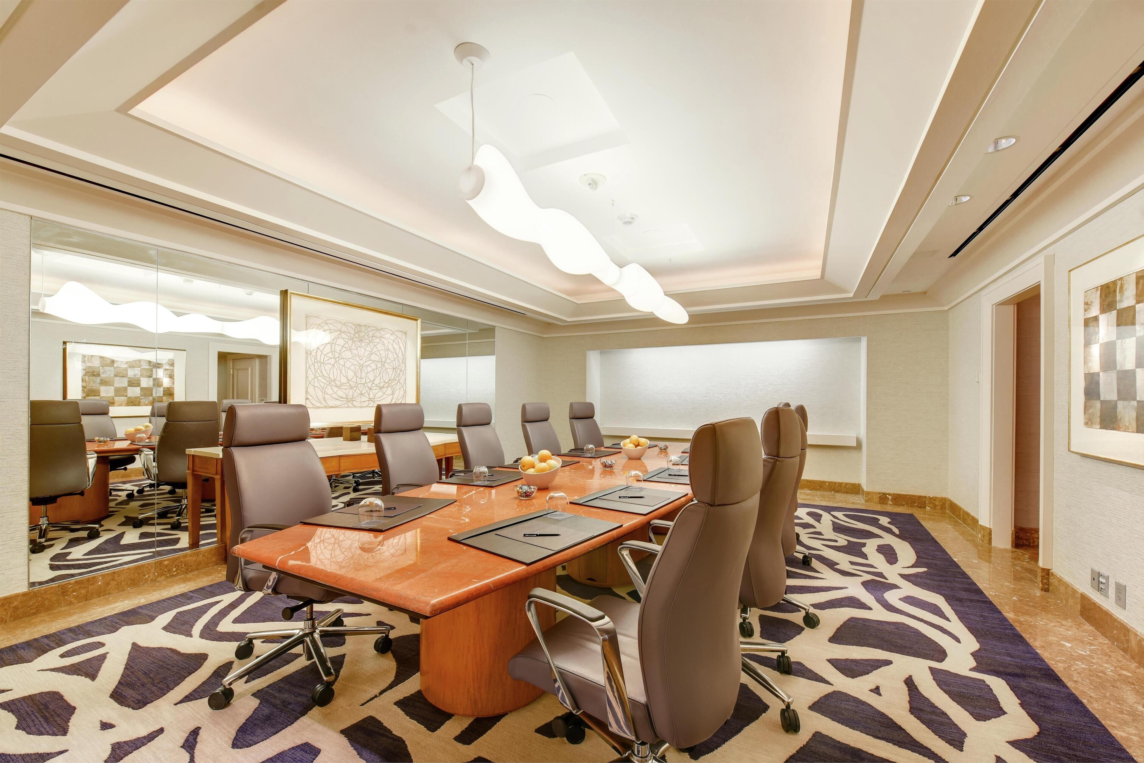 A conference room with a long table, multiple chairs, and a large mirror.