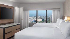 A hotel room with a large bed, a TV mounted on the wall, and a city view through the window. - Hilton Los Angeles Airport (Los Angeles)
