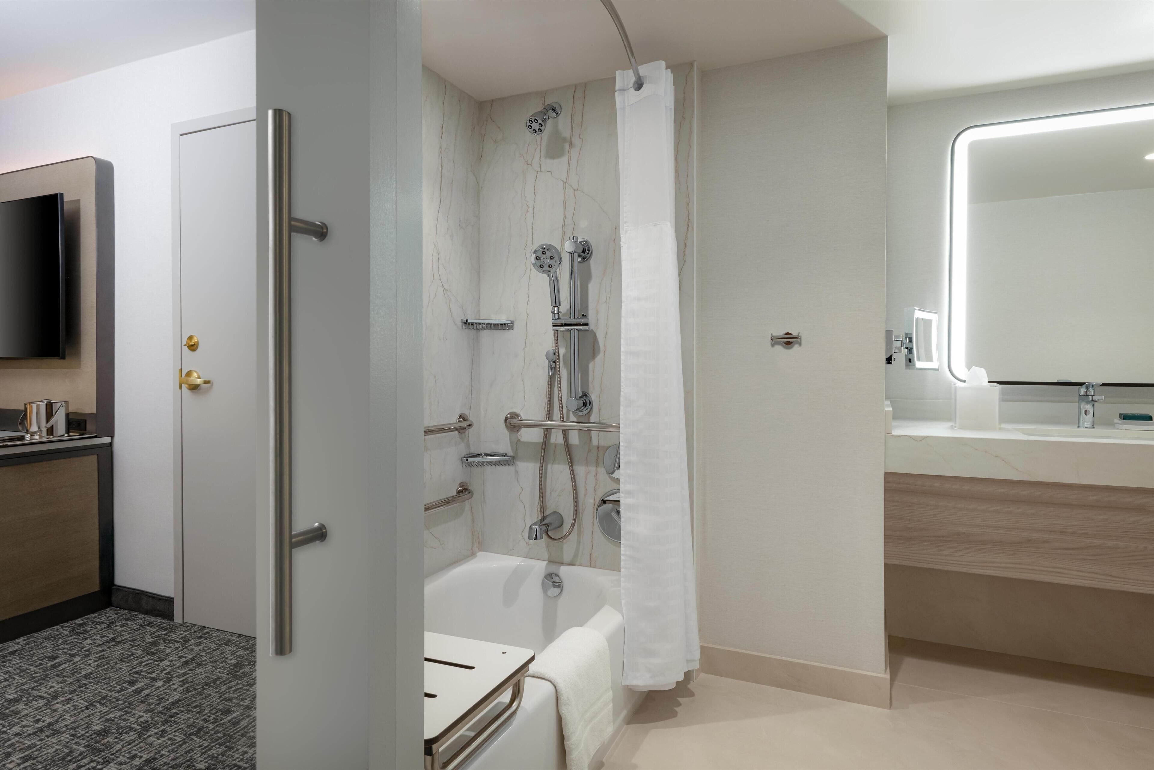 Un baño moderno con bañera, ducha y tocador con espejo.