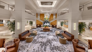 A spacious lobby with a central staircase, seating areas, and a chandelier. - Hilton Los Angeles Airport (Los Angeles)