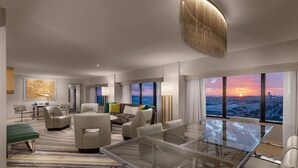 A modern hotel room with a large glass table, comfortable seating, a city view, and a large artwork on the wall. - Hilton Los Angeles Airport (Los Angeles)