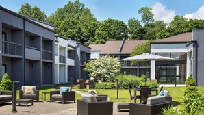 A courtyard with outdoor seating, a small tree, and a building with balconies. - Courtyard by Marriott Poughkeepsie (Poughkeepsie)