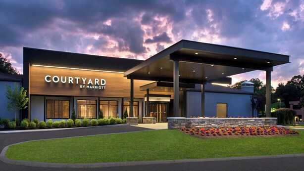A Courtyard by Marriott hotel with a modern design, large windows, and a well-maintained lawn. - Courtyard by Marriott Poughkeepsie (Poughkeepsie)
