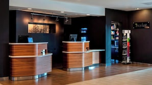 A reception area with two wooden reception desks, a wall-mounted screen, and a vending machine labeled "market". - Courtyard by Marriott Poughkeepsie (Poughkeepsie)