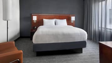 A hotel room with a large bed, two bedside tables, a desk, and a chair.