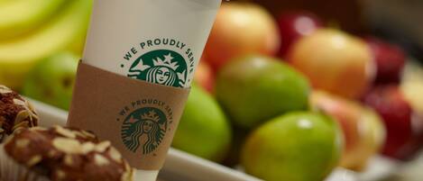 Una taza de Starbucks, un muffin y un plato de manzanas.