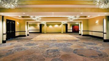 A spacious hall with patterned carpet, recessed lighting, and chandeliers.