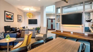 A modern hotel lobby with a seating area, a large flat-screen TV, and a chandelier. - Sheraton Portsmouth Harborside Hotel (Portsmouth)