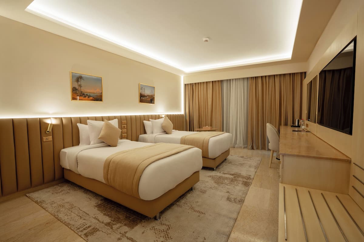 A modern hotel room with two beds, a desk, and a large mirror.