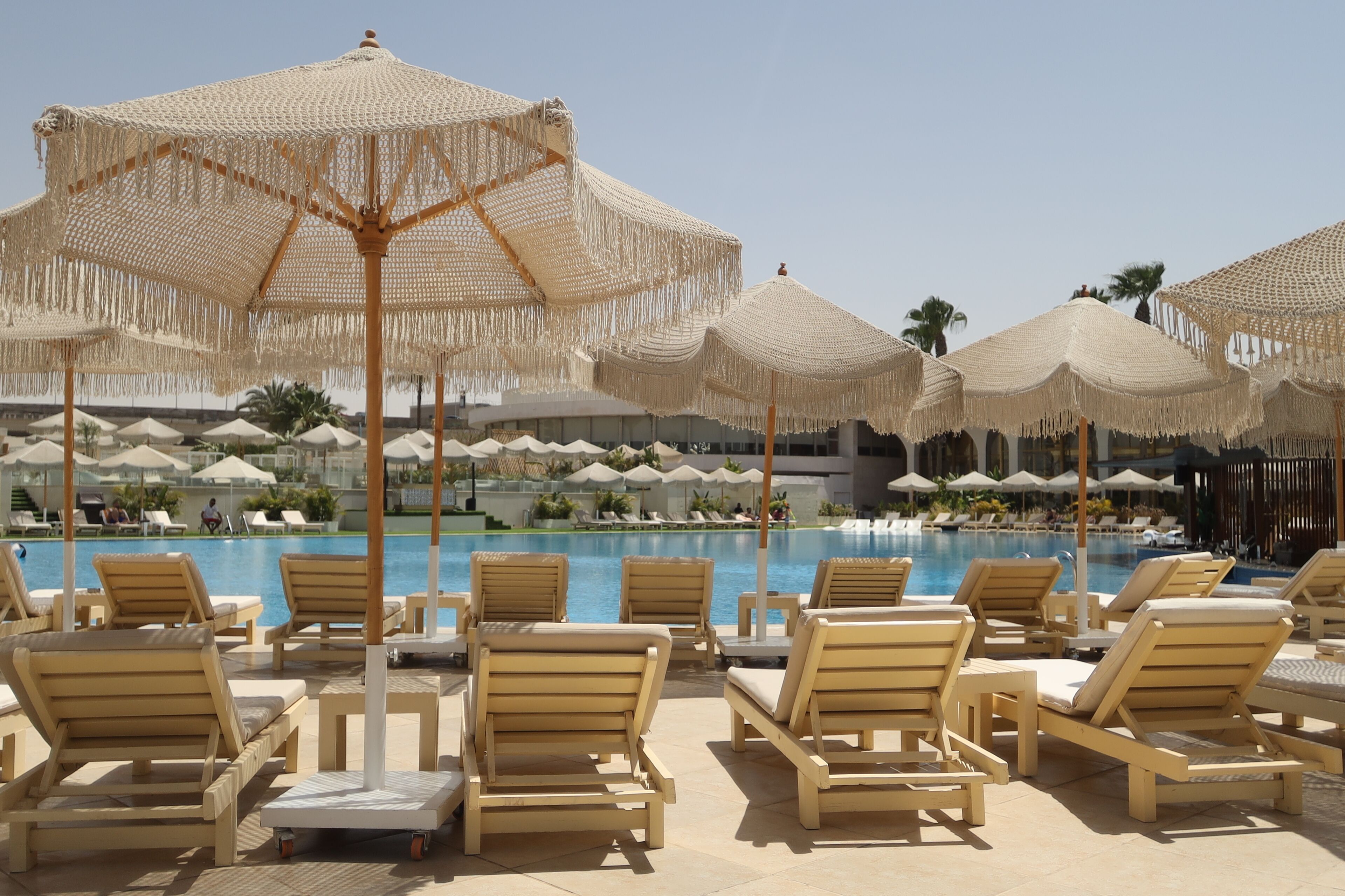 A poolside area with lounge chairs and thatched umbrellas.