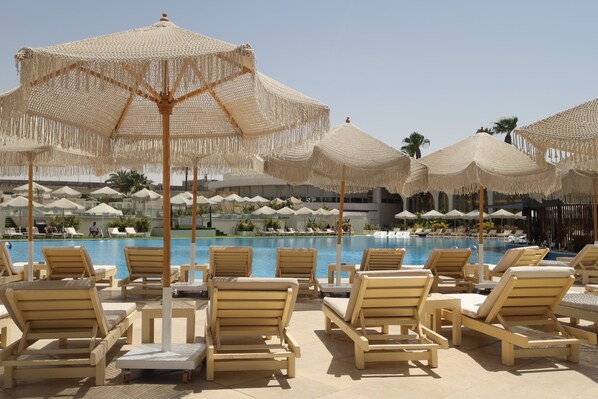 A poolside area with lounge chairs and thatched umbrellas.