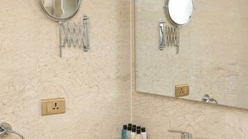 Un baño con lavamanos, espejo, perchero para toallas y artículos de aseo.