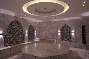 Un interior modern amb una làmpada de sostre circular, parets de marbre i una zona d'estar central.