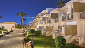 Un camí que condueix a un edifici modern amb balcons i un jardí ben cuidat.
