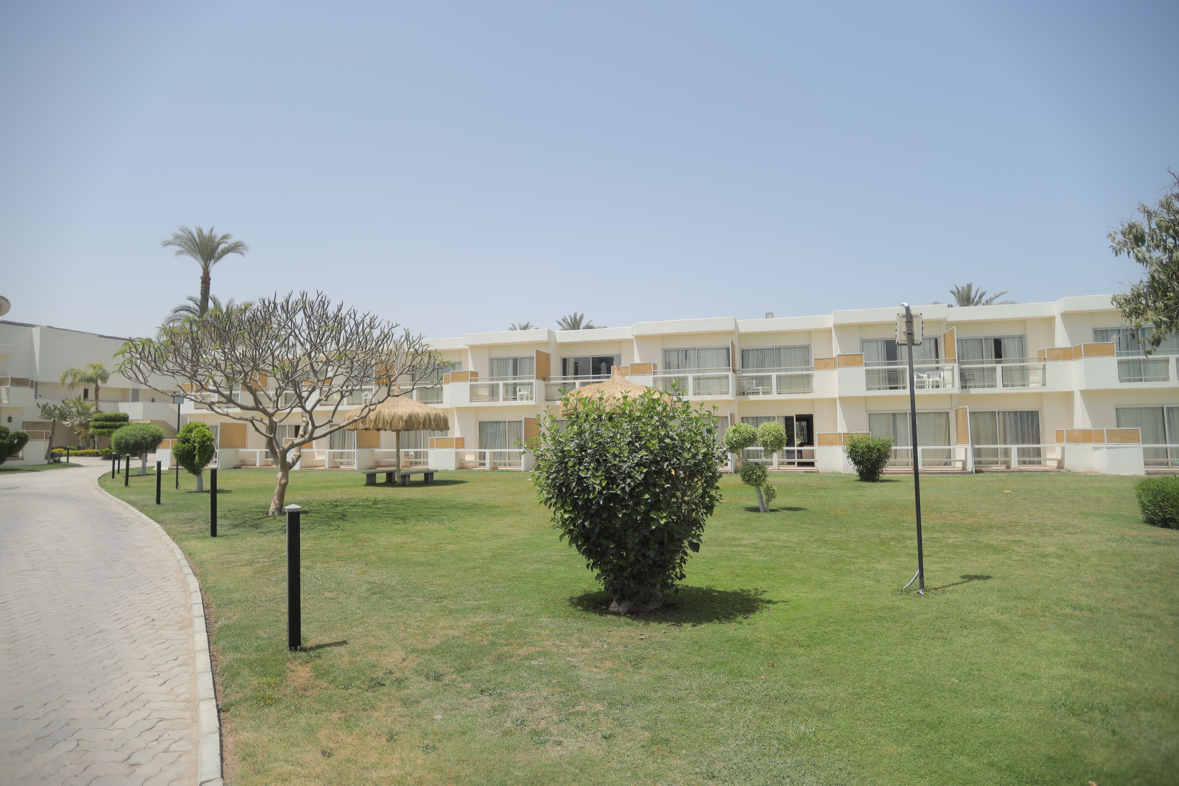 A hotel with a courtyard, a paved walkway, and a building with multiple balconies.