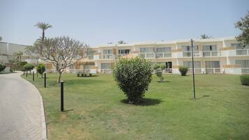 A hotel with a courtyard, a paved walkway, and a building with multiple balconies.