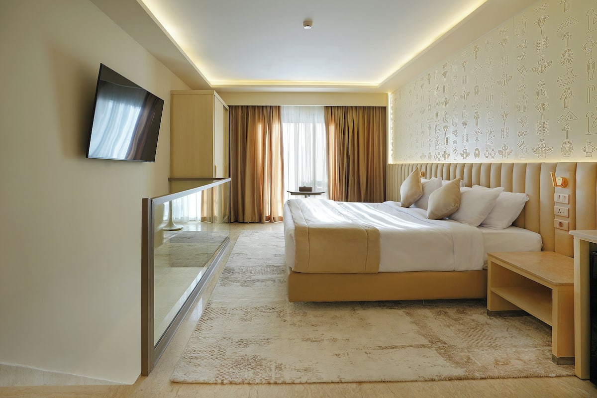 A modern hotel room with a large bed, bedside table, and a television mounted on the wall.