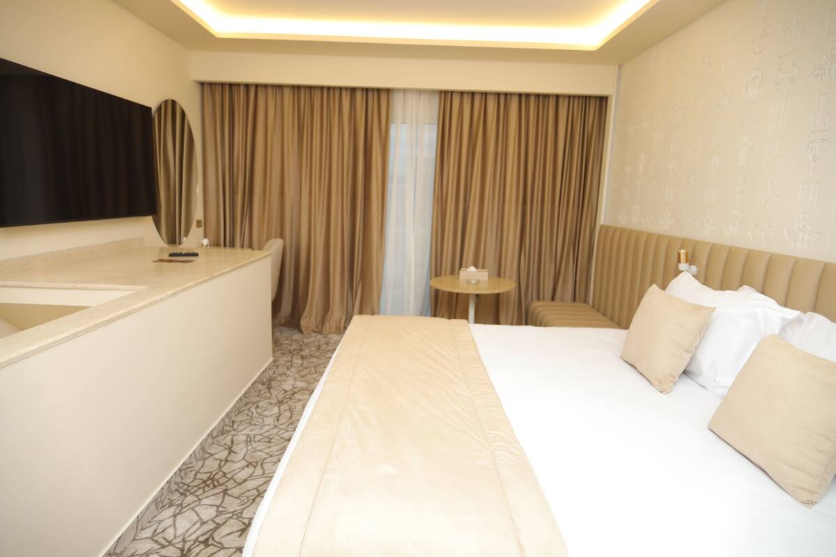A hotel room with a bed, bedside table, and a large mirror.