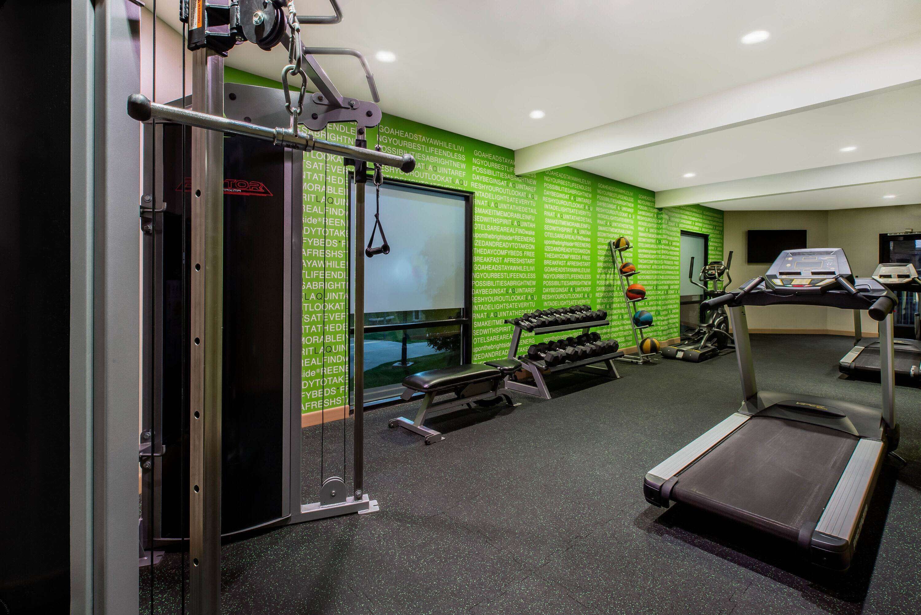 Une salle de sport équipée de tapis de course, d’haltères et d’un banc de musculation.