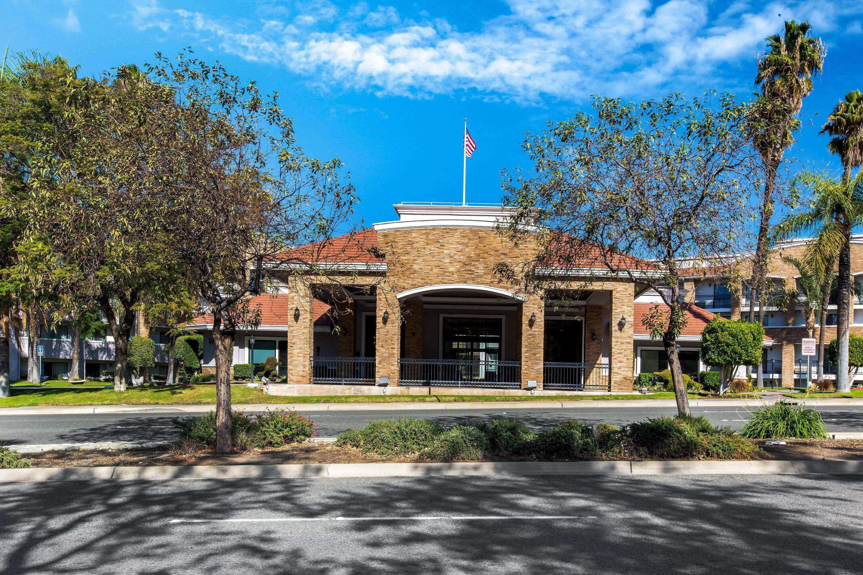 A building with a brick facade, a flagpole with an American flag, and a curved entrance.