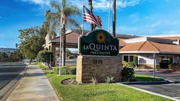 La Quinta Inn & Suites features a welcoming entrance with a prominent sign and lush surroundings.