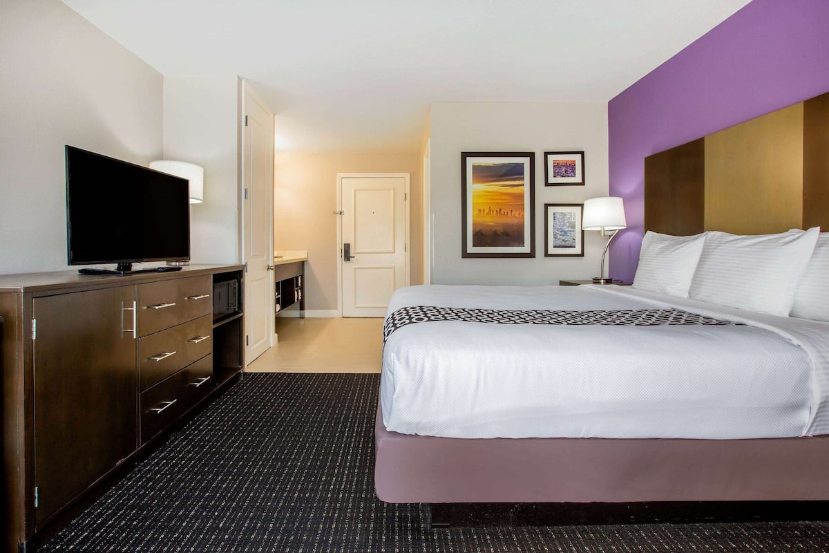 Une chambre d’hôtel comprenant un lit, une télévision, un bureau et une porte donnant accès à une salle de bain.