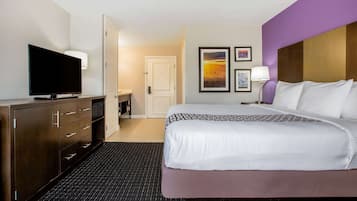A hotel room with a bed, a television, a desk, and a door leading to a bathroom.