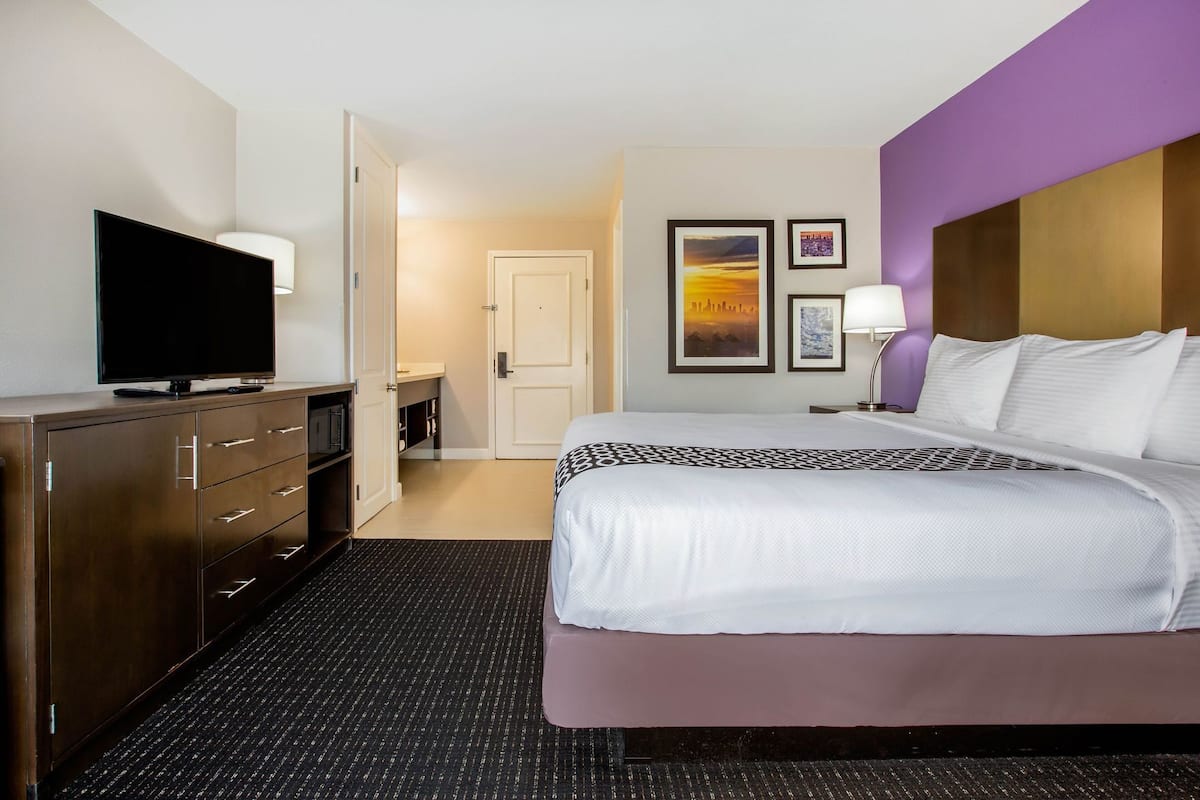 Une chambre d’hôtel comprenant un lit, une télévision, un bureau et une porte donnant accès à une salle de bain.