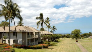 A golf course with a clubhouse, palm trees, and a clear sky. - Wailea Grand Champions - Maui Condo & Home (Kihei)
