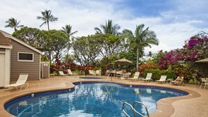 A swimming pool with a curved edge, surrounded by lounge chairs and palm trees. - Wailea Grand Champions - Maui Condo & Home (Kihei)