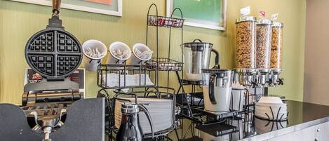 Una barra de desayuno con máquina para gofres, máquinas de café y dispensadores de condimentos.
