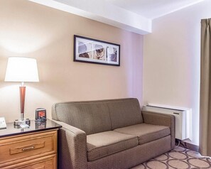 A hotel room with a sofa, a lamp, a framed picture on the wall, and a window with curtains. - Comfort Inn Riviere-du-Loup (Rivière-du-Loup)