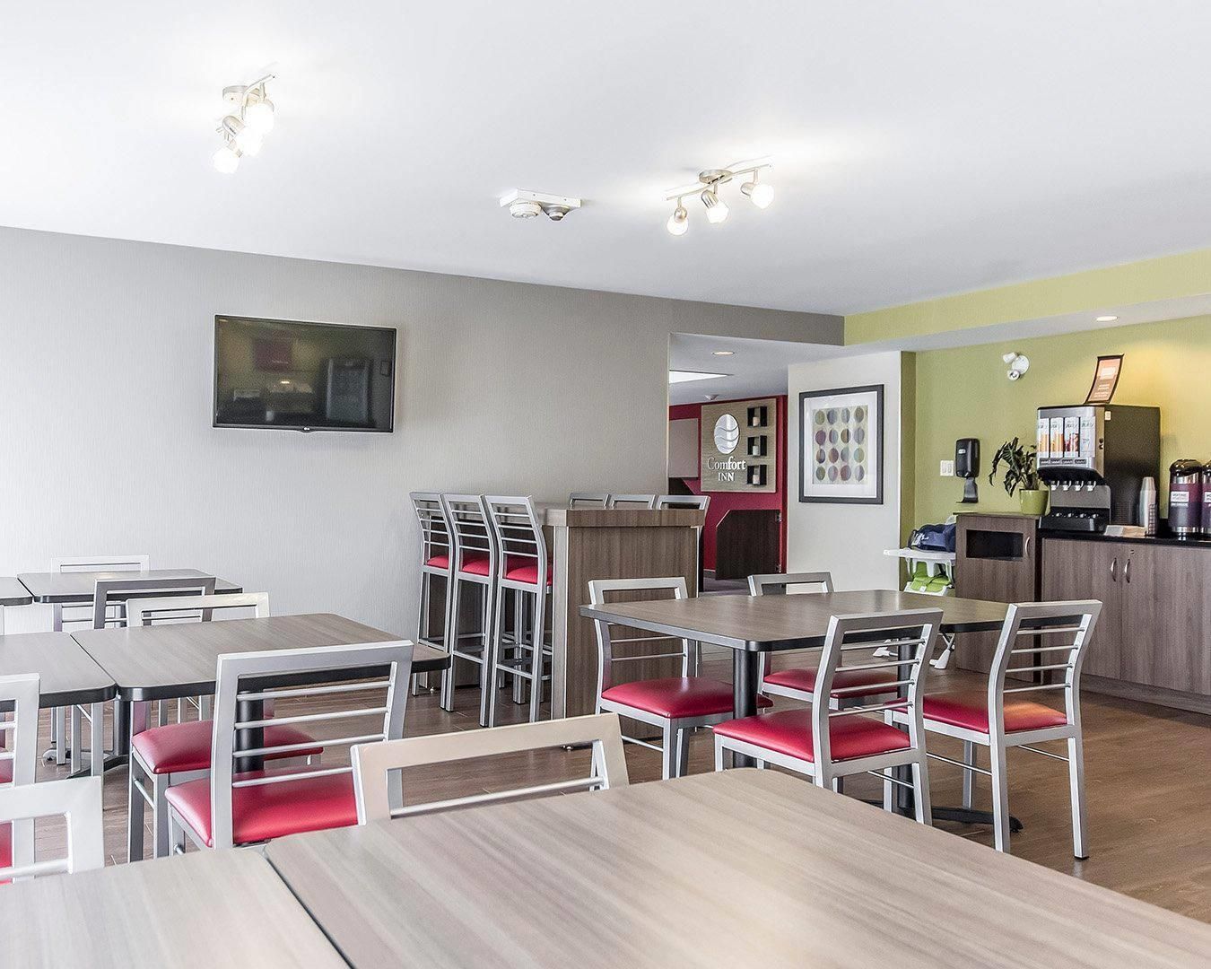A hotel room with a dining area, a kitchenette, and a bed.
