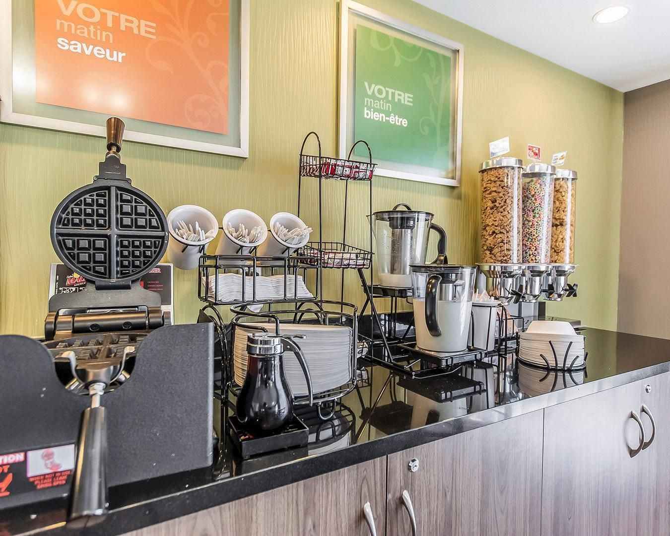 Una barra de desayuno con máquinas para gofres, cafeteras y dispensadores de condimentos.