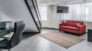 Ein modernes Wohnzimmer mit einer Couch, einem Schreibtisch und einem Flachbildfernseher.