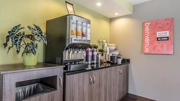 A reception area with a coffee machine, a potted plant, and a welcome sign.