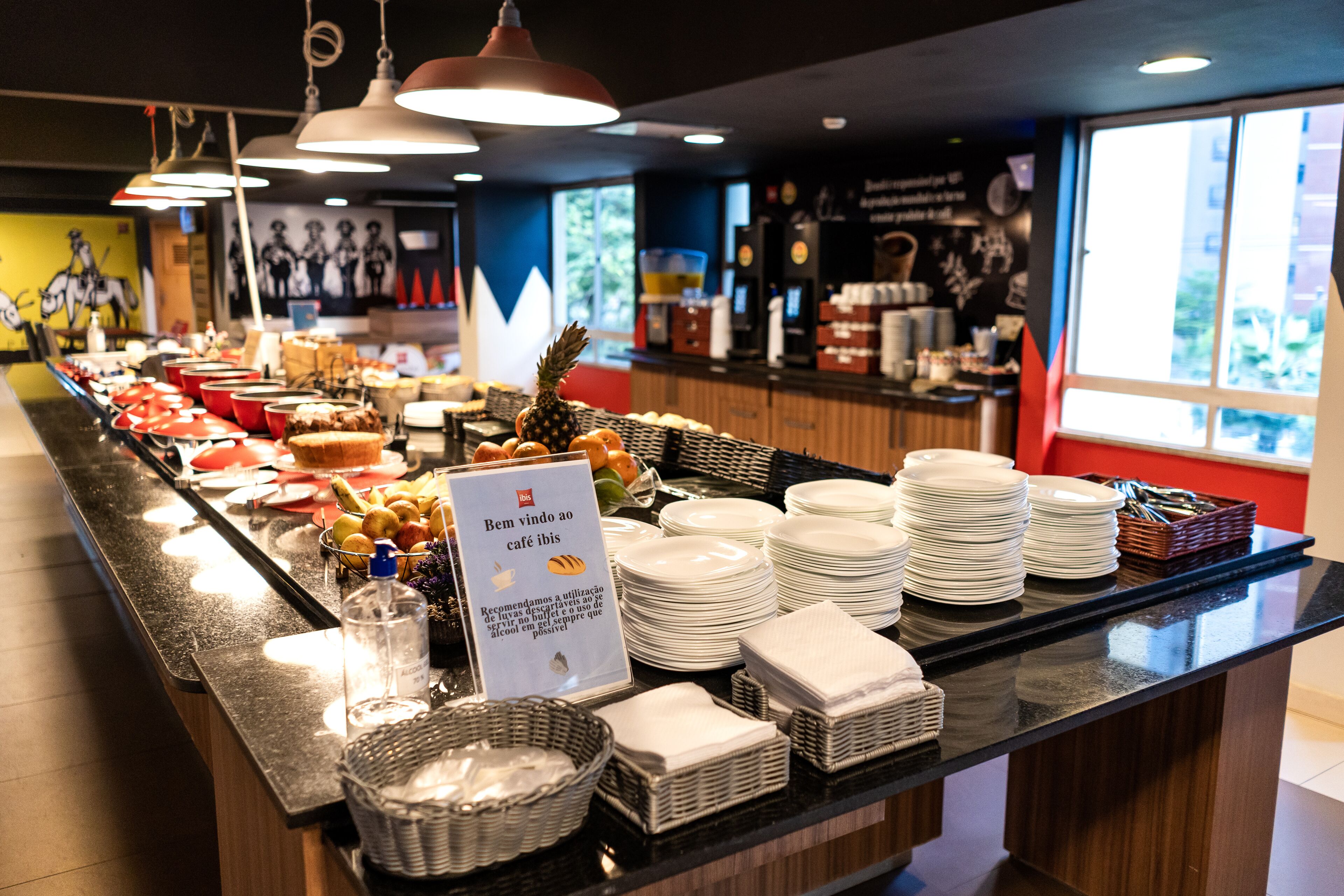 A buffet counter with various food items and stacked plates.