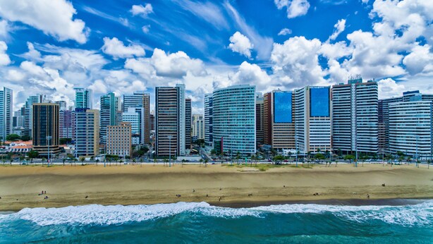 Un paisaje urbano costero con rascacielos, una playa de arena y el océano.