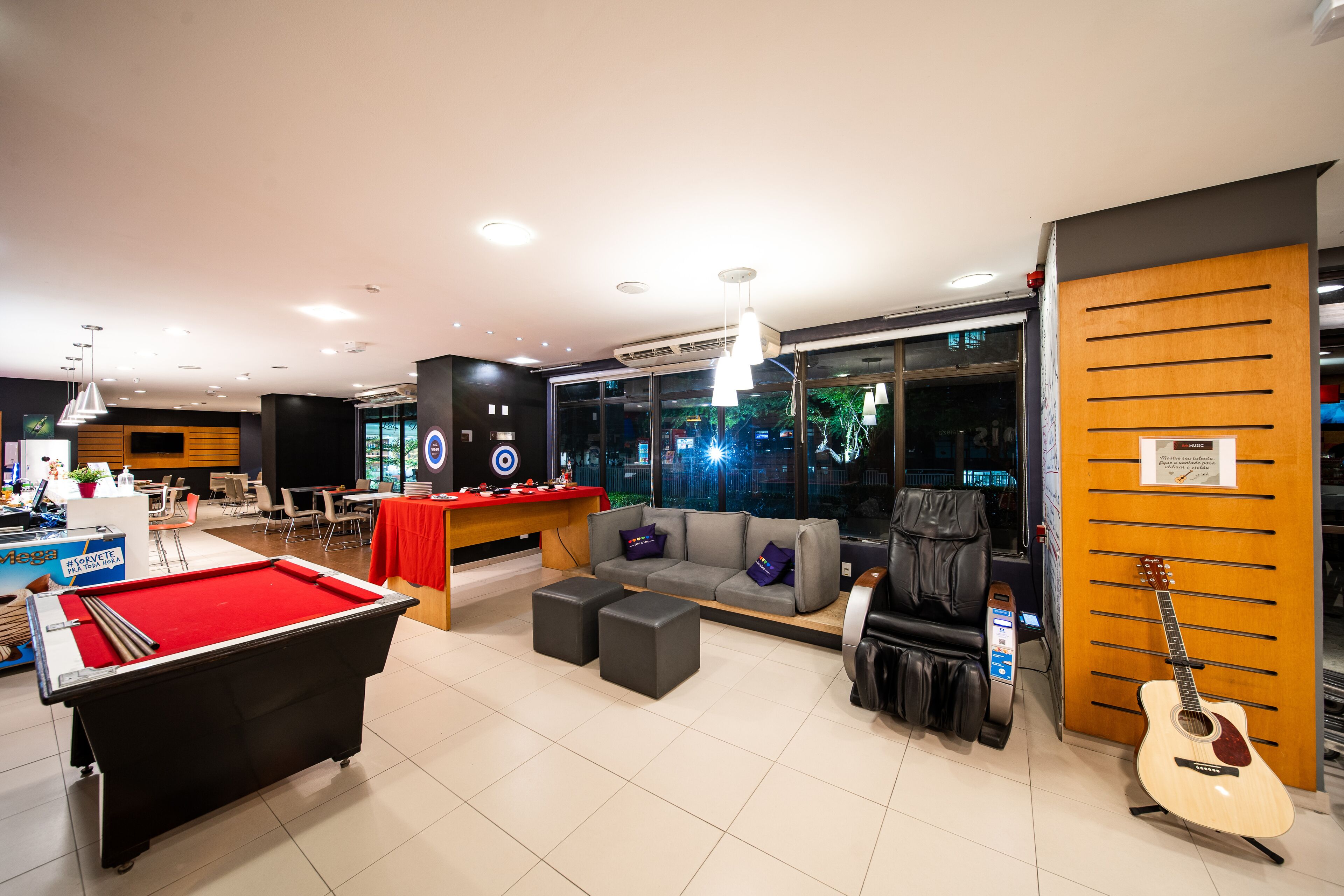 A modern lounge area with a pool table, comfortable seating, and a guitar.