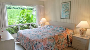 Une chambre à coucher avec un lit, deux tables de chevet avec des lampes, une fenêtre avec des rideaux et un tableau encadré au mur.