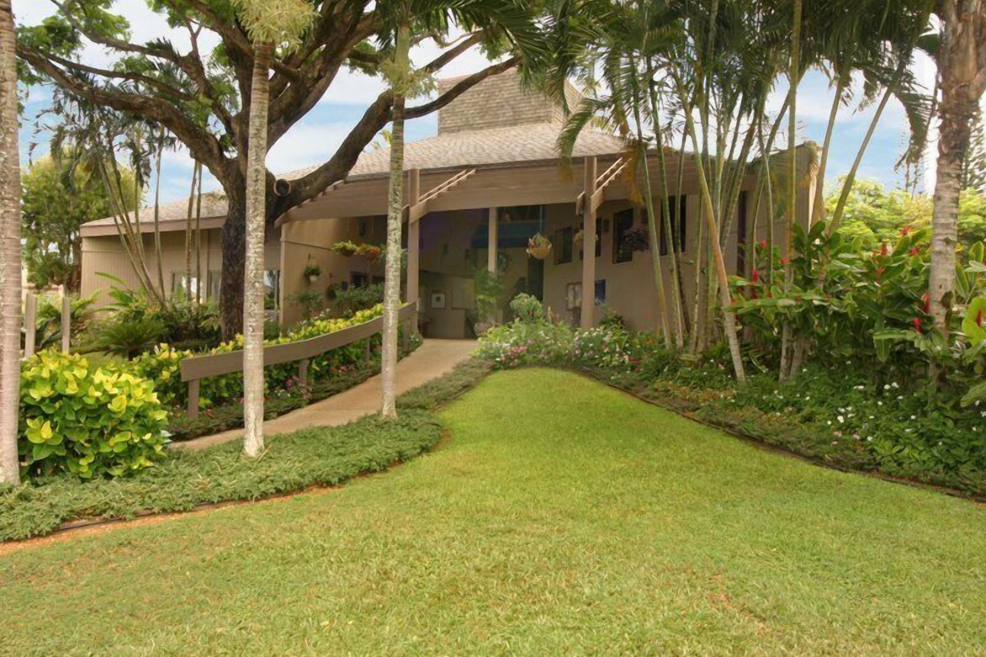 Un edificio con un paseo techado, rodeado de exuberante vegetación y palmeras.