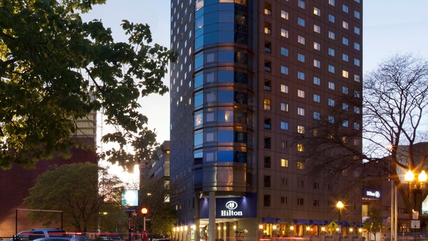 Un hotel moderno de gran altura con fachada de vidrio, varios pisos y un letrero de Hilton visible en la base.