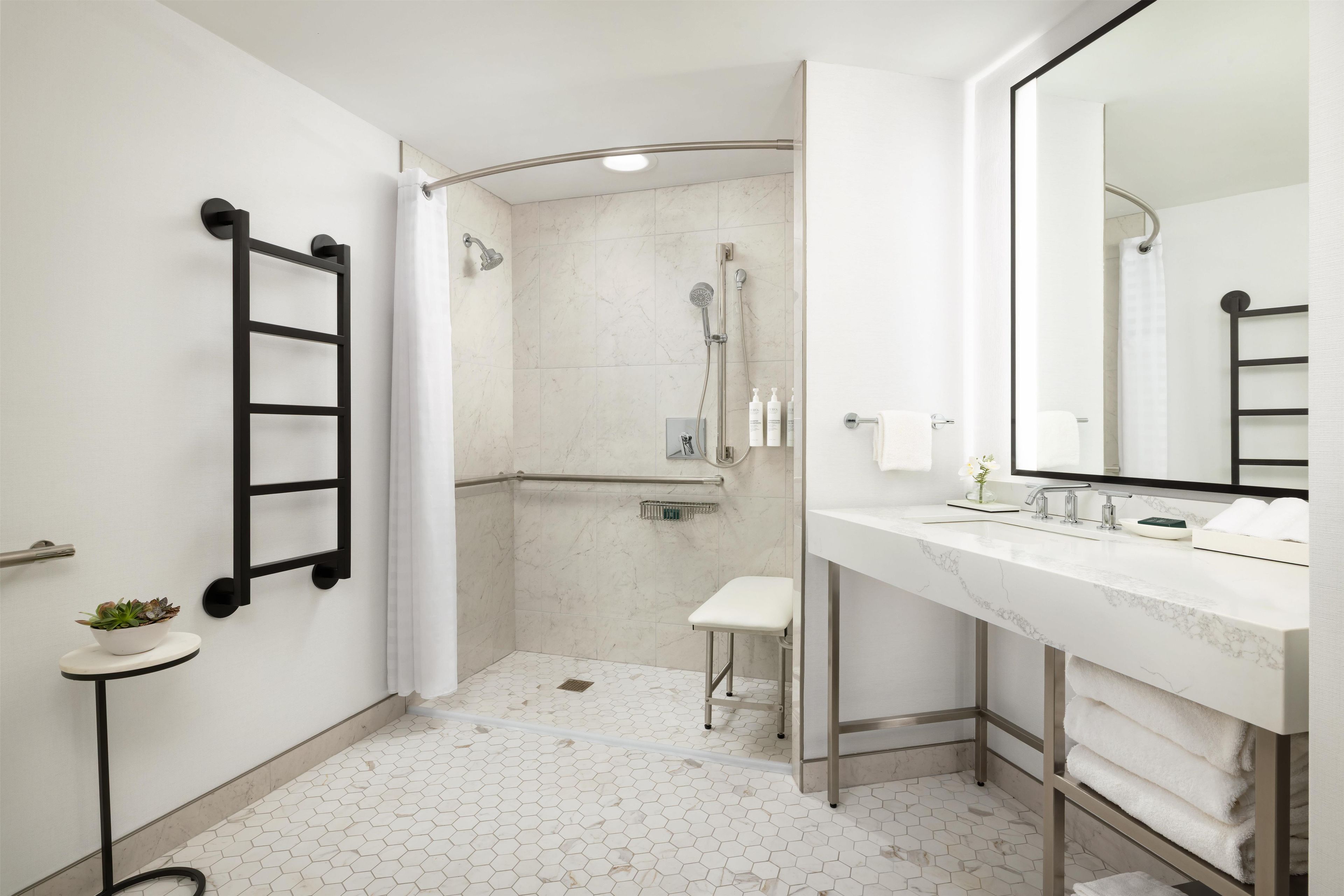 Un baño moderno con ducha, inodoro y lavamanos, con una paleta de colores blanco y gris.