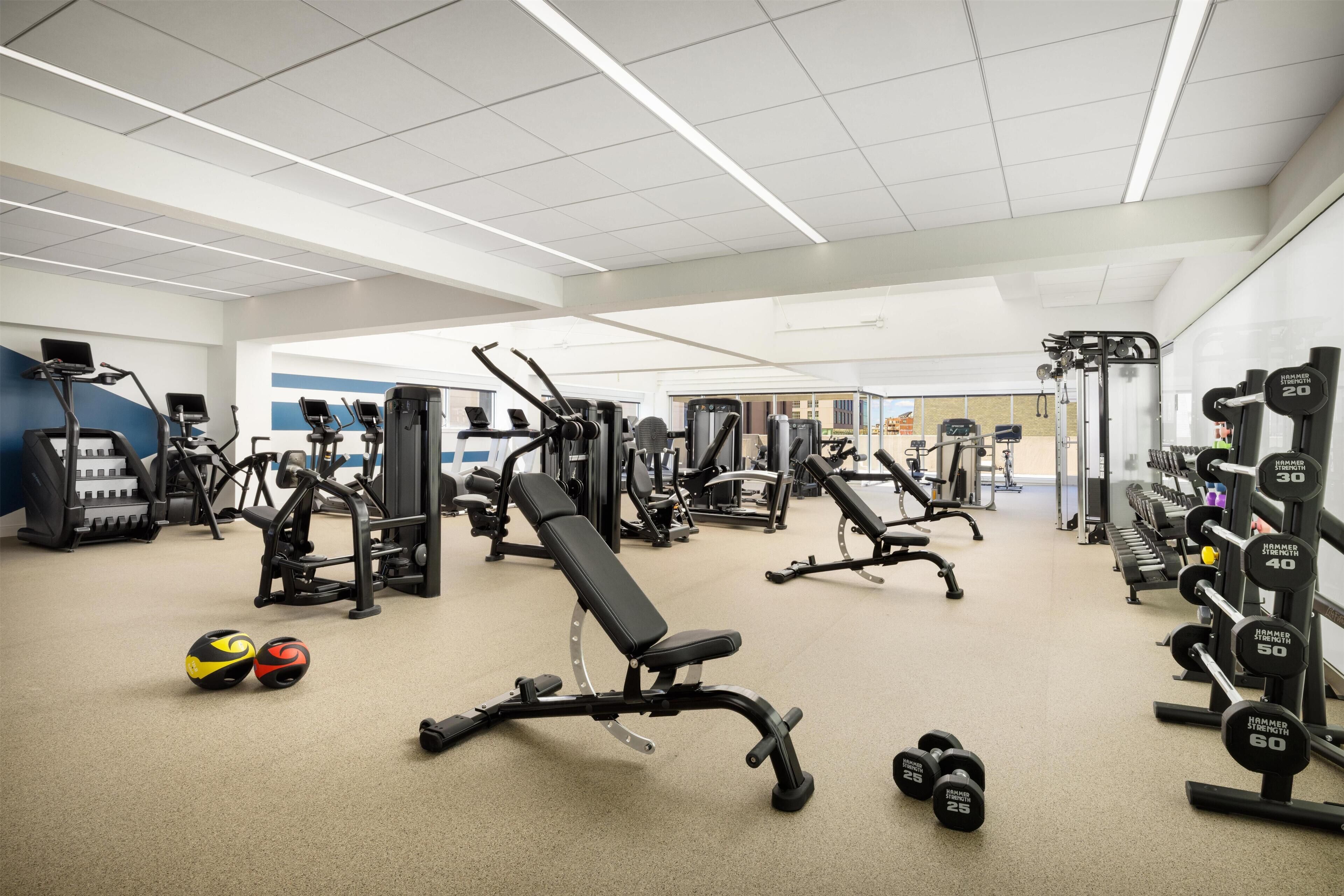 Een sportschool met diverse fitnessapparaten, waaronder loopbanden, krachtapparaten en gewichten.