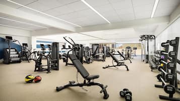 Een sportschool met diverse fitnessapparaten, waaronder loopbanden, krachtapparaten en gewichten.