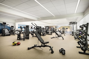 Een sportschool met diverse fitnessapparaten, waaronder loopbanden, krachtapparaten en gewichten.