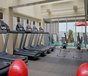 A gym with treadmills, exercise balls, and a view of the outdoors through large windows. - Hilton Boston Back Bay (Boston)